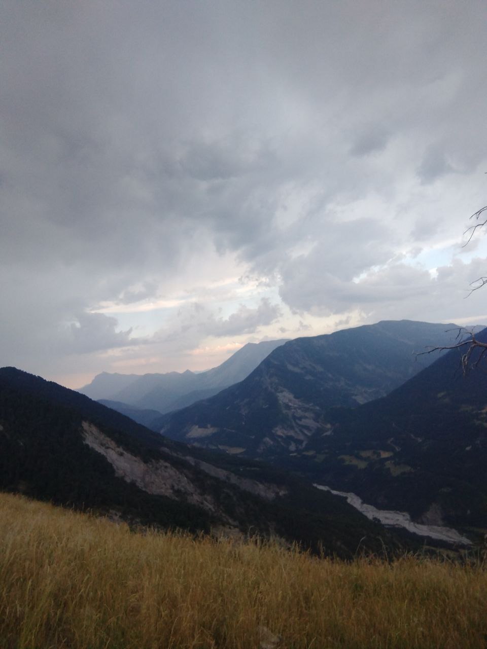 Vallée de montagne sous un ciel d'orage, vue depuis un alpage