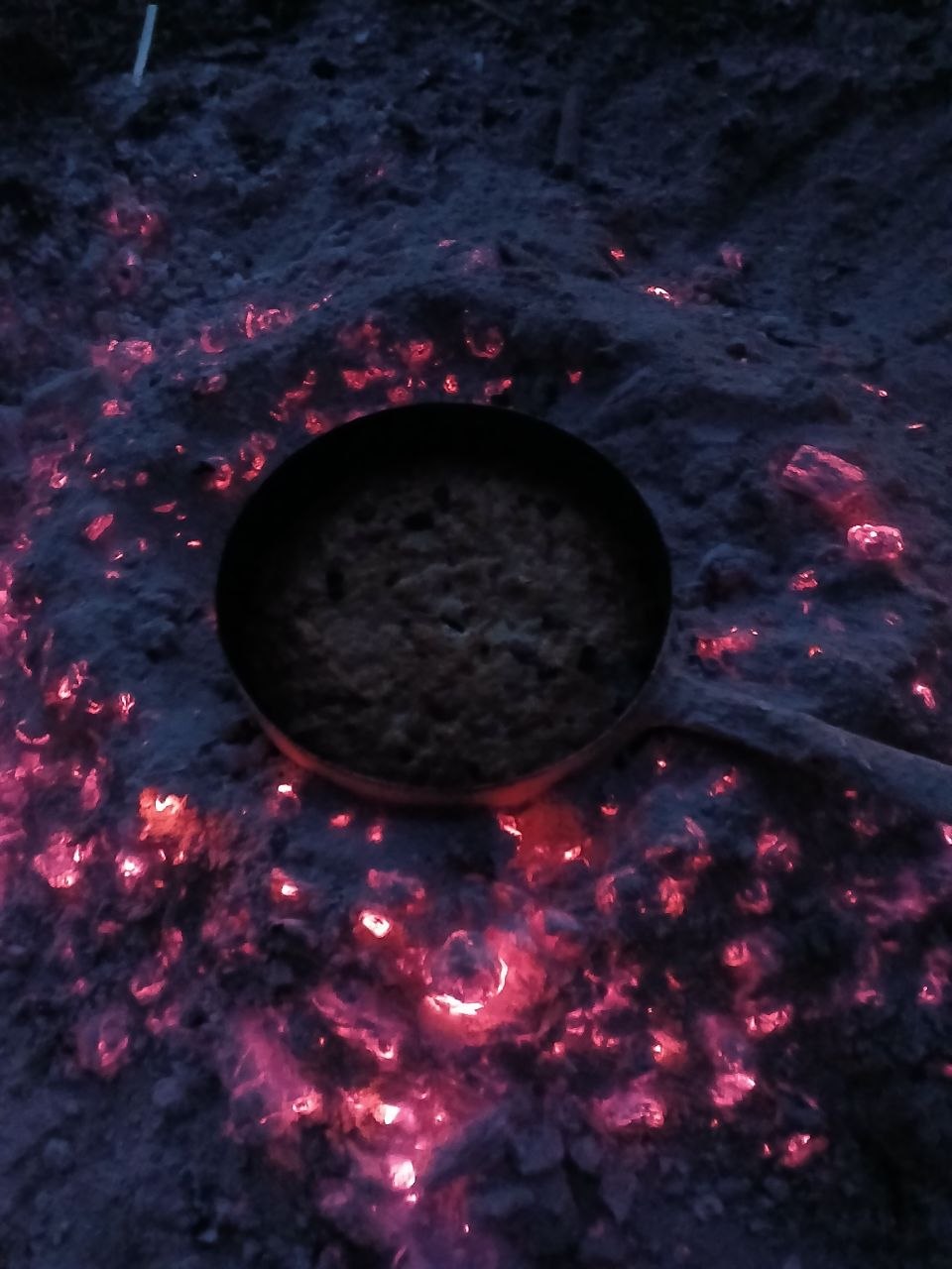 La casserole en cuisson au milieu des braises rougeoyantes