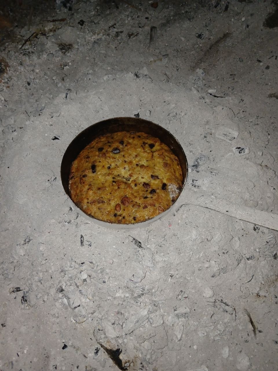Un pudding doré cuit dans une casserole, posé sur la cendre